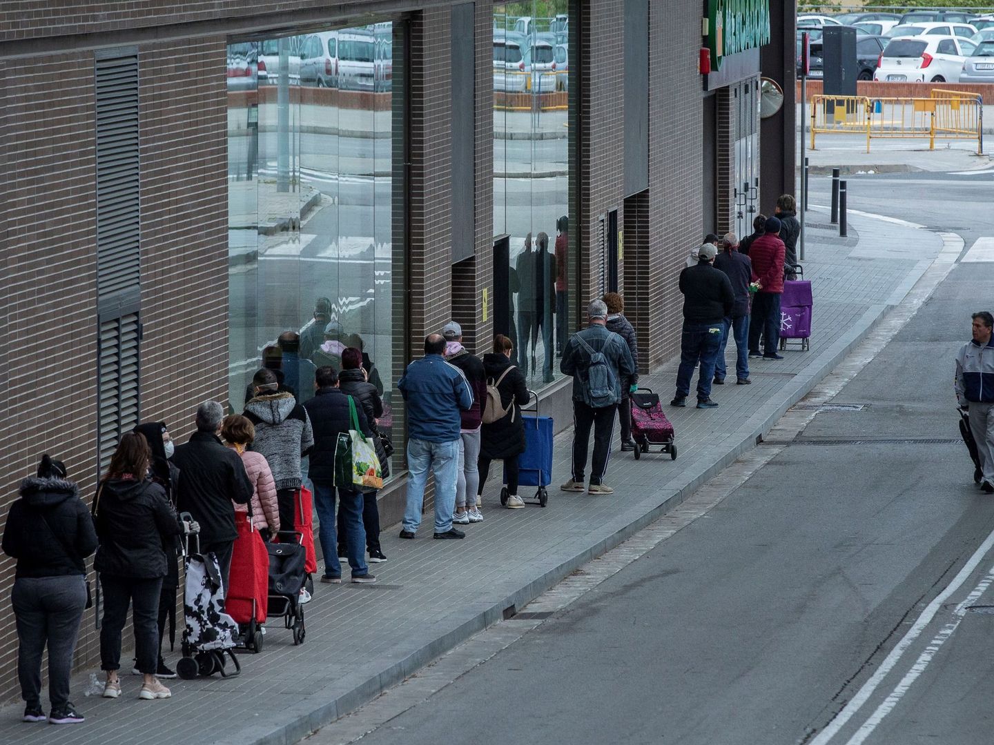 Varias personas esperan para entrar en un supermercado de Nou Barris, Barcelona. (EFE)