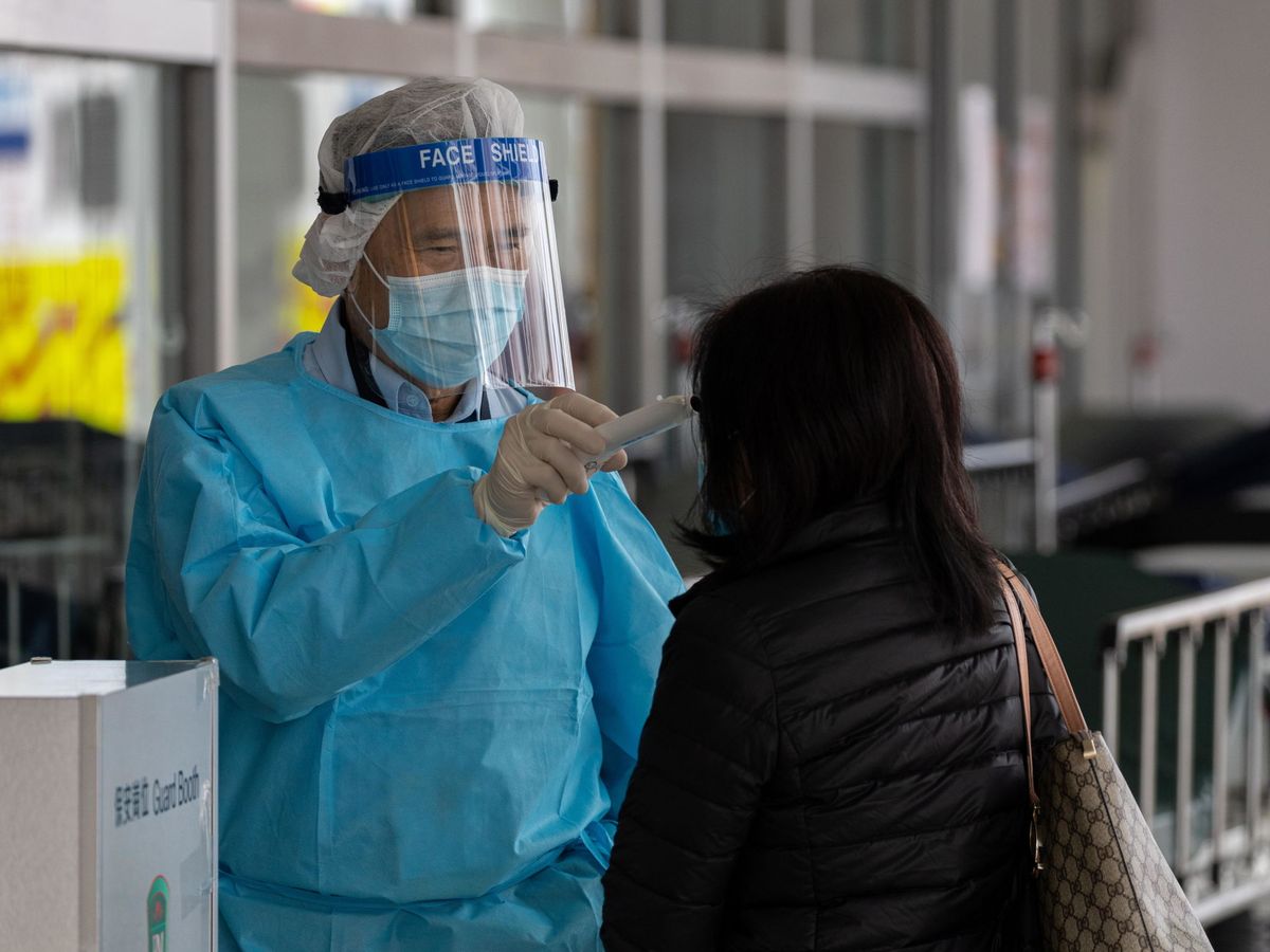 Foto: Un guardia mide la temperatuva a una mujer en el Hospital Princess Margaret, en Hong Kong. (EFE)