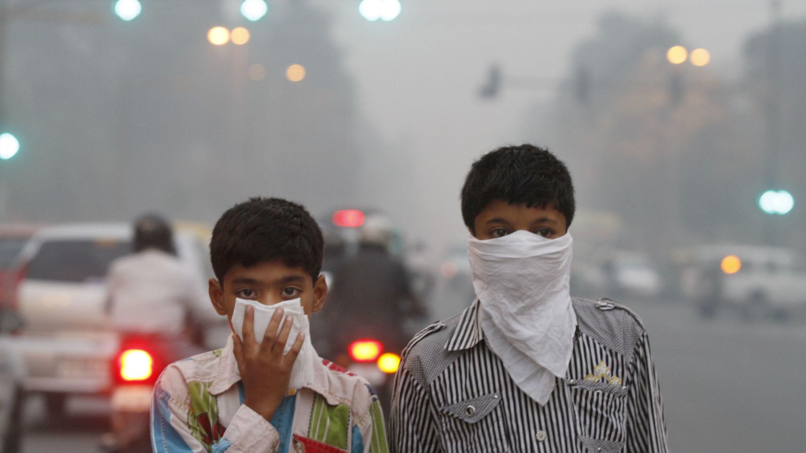 Foto: Dos niños se tapan el rostro para protegerse de la contaminación en Nueva Delhi, India (Sanjeev Verma/Getty Images)