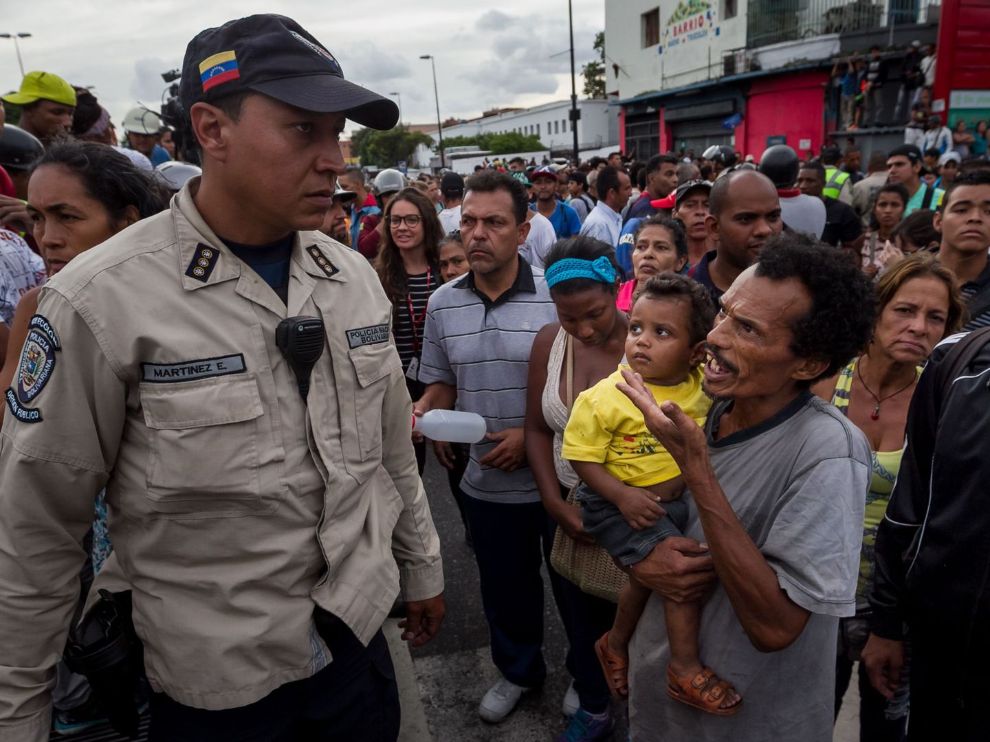 Un hombre con un niño en brazos grita consignas a un miembro de la Policía Nacional Bolivariana (PNB) en Caracas, el 14 de junio de 2016 (EFE)