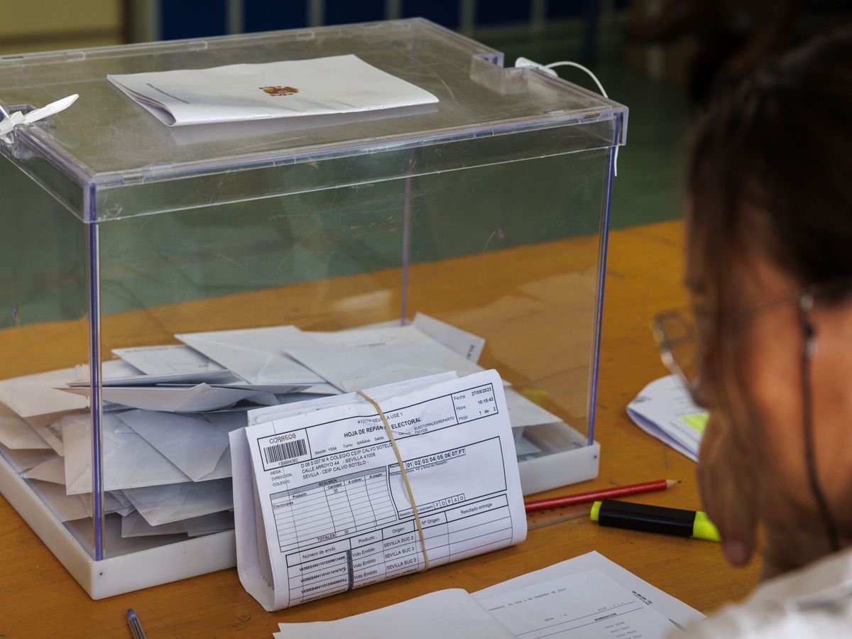 Foto: Un envío conteniendo votos por correo junto a la urna en un colegio electoral. (EFE/Julio Muñoz)