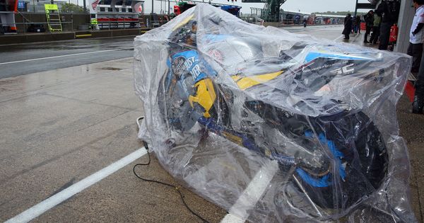 Foto: Una moto en el paddock de Silverstone, tapada por un plástico por la lluvia. (EFE)