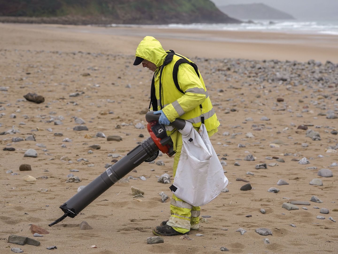 Un operario recoge 'pellets' de plástico este jueves en la playa de Vega, Asturias. (EFE/Paco Paredes)