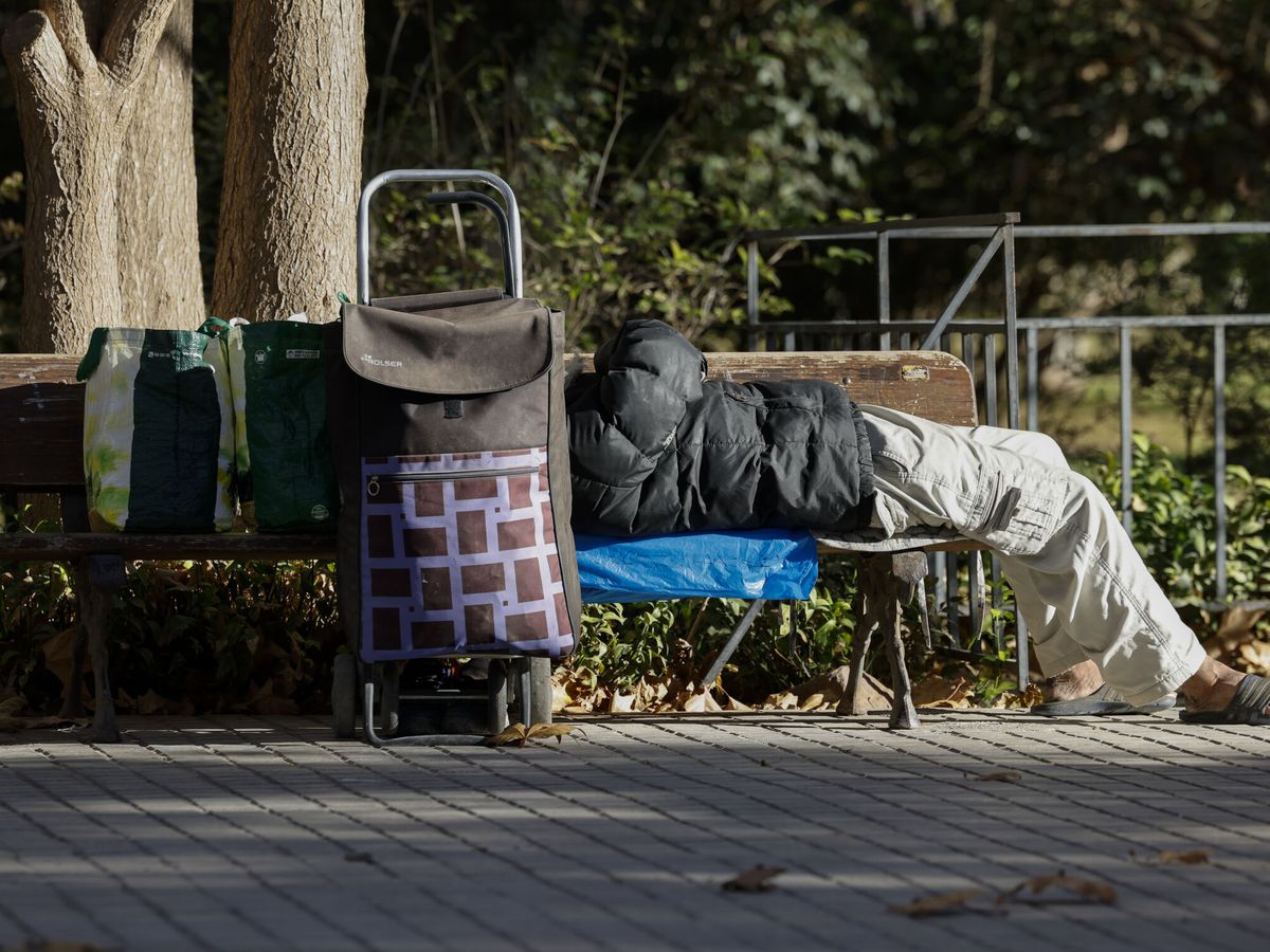 Foto: Una persona sin hogar descansa junto a sus pertenencias en un banco público. (EFE/Ana Escobar)
