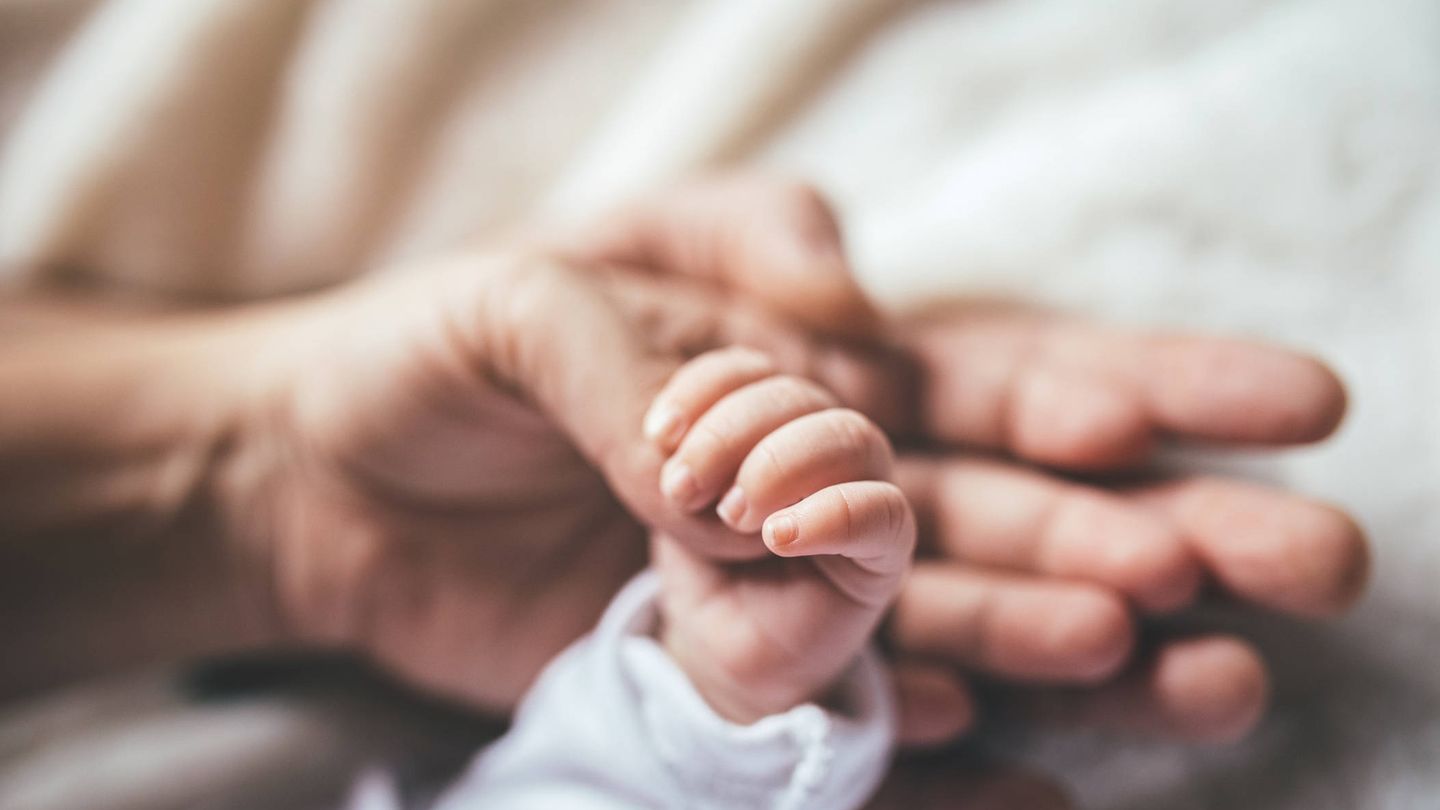 Placer al acariciar la mano de un bebé. (iStock)