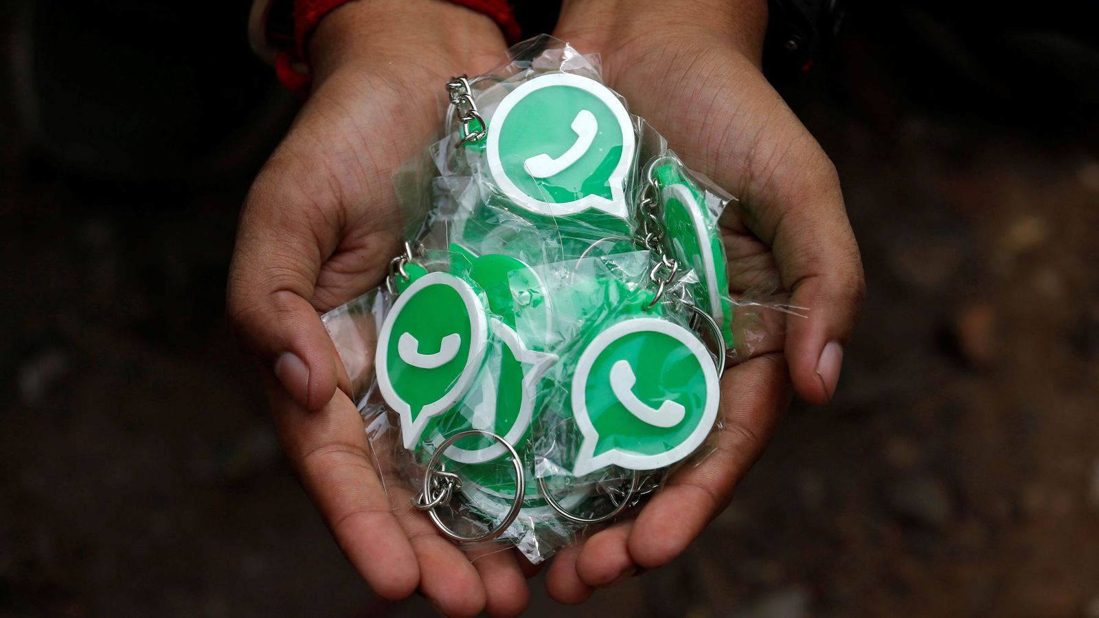 Foto: Una persona sostiene llaveros con el símbolo de WhatsApp. (Reuters)