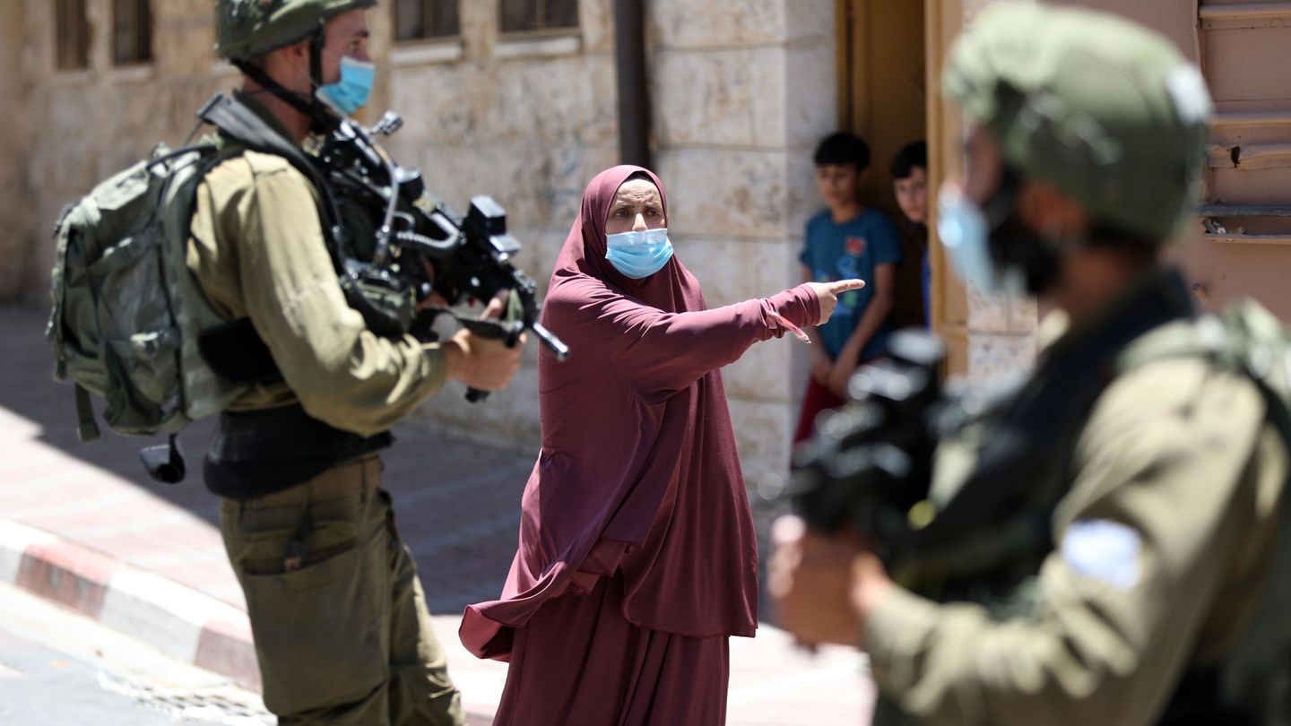 Una mujer palestina discute con soldados israelíes en Hebrón, después de que los militares detuvieran a su hijo en un control rutinario. (EFE)