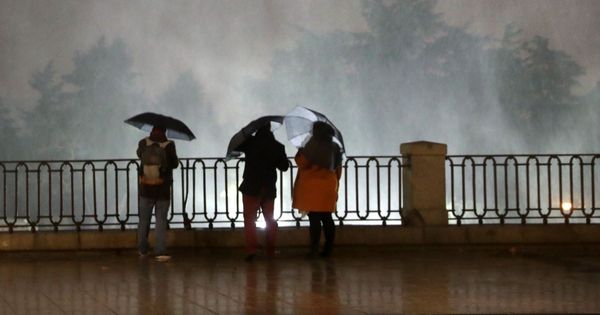 Foto: Varias personas observando las partículas de agua en suspensión debido al fuerte viento en la plaza de Oriente de Madrid la semana pasada. (EFE)