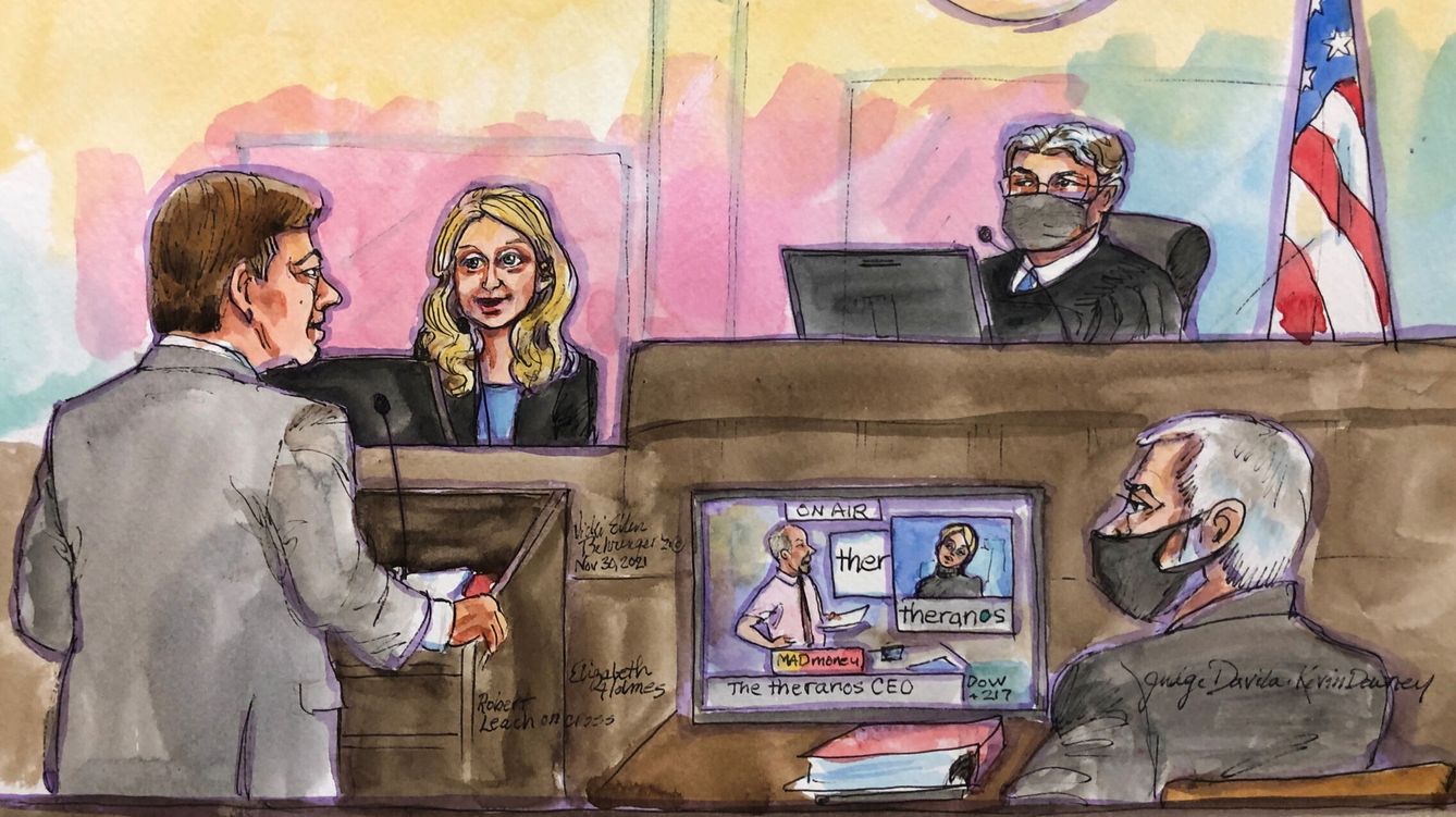 Theranos founder Elizabeth Holmes is cross examined by prosecutor Robert Leach as an image of CNBC program Mad Money appears on a screen at Robert F. Peckham U.S. Courthouse during her trial, in San Jose, California, U.S., November 30, 2021 in this courtroom sketch. REUTERS Vicki Behringer