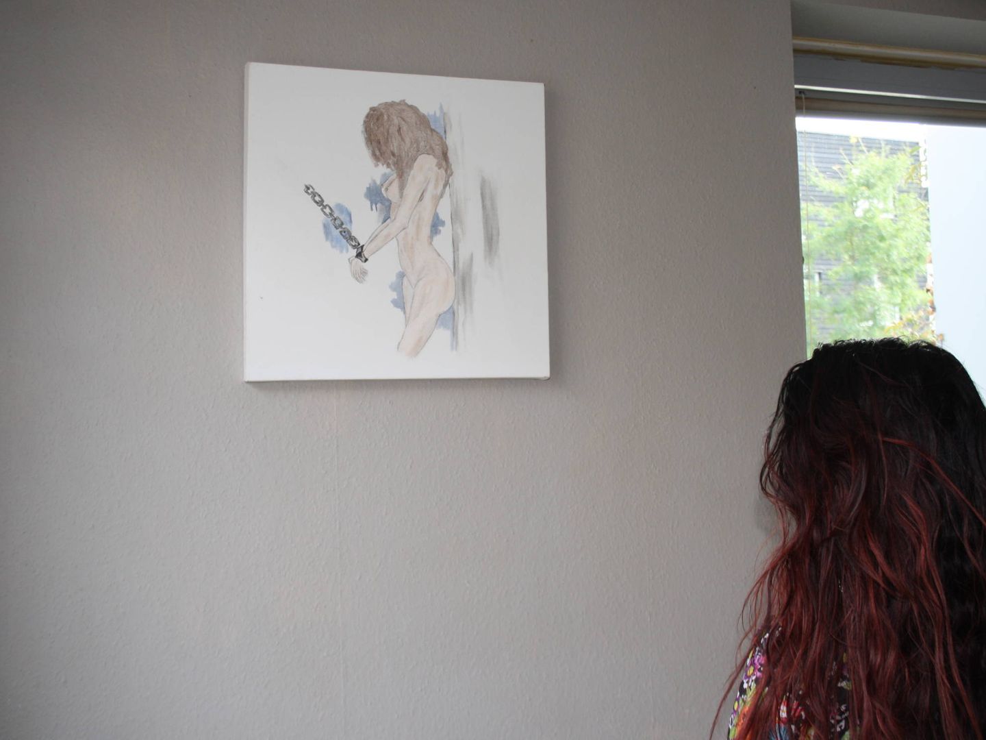 Alejandra de espaldas a su dibujo, que denuncia el proxenetismo escolar en Holanda. 