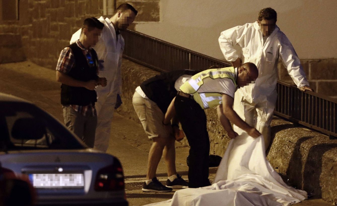 Efectivos policiales junto al cuerpo de una de las tres personas que han resultado muertas. (EFE)