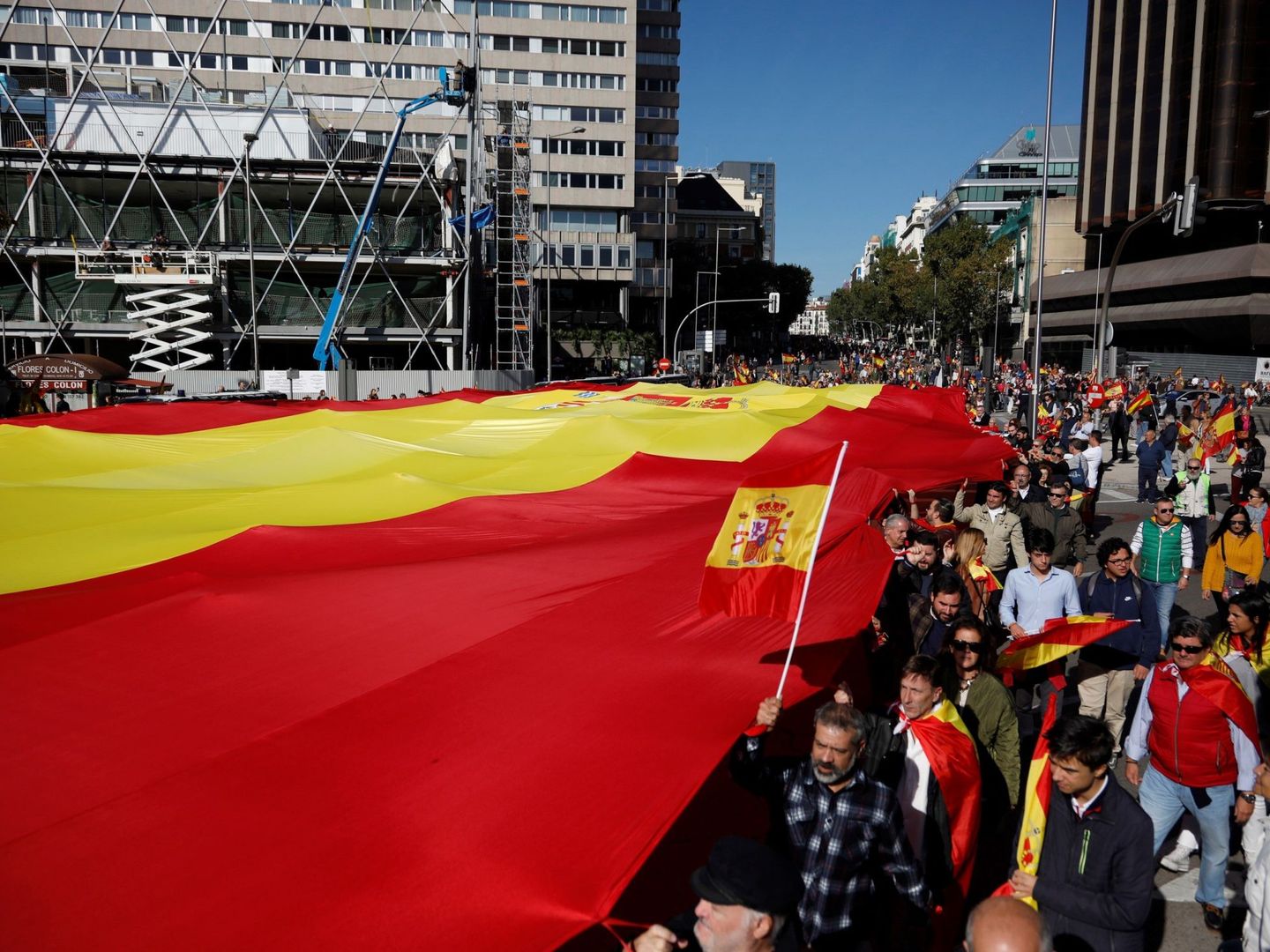 Decenas de personas sostienen la bandera de España de 1.000 metros cuadrados en el acto de Vox. (EFE)