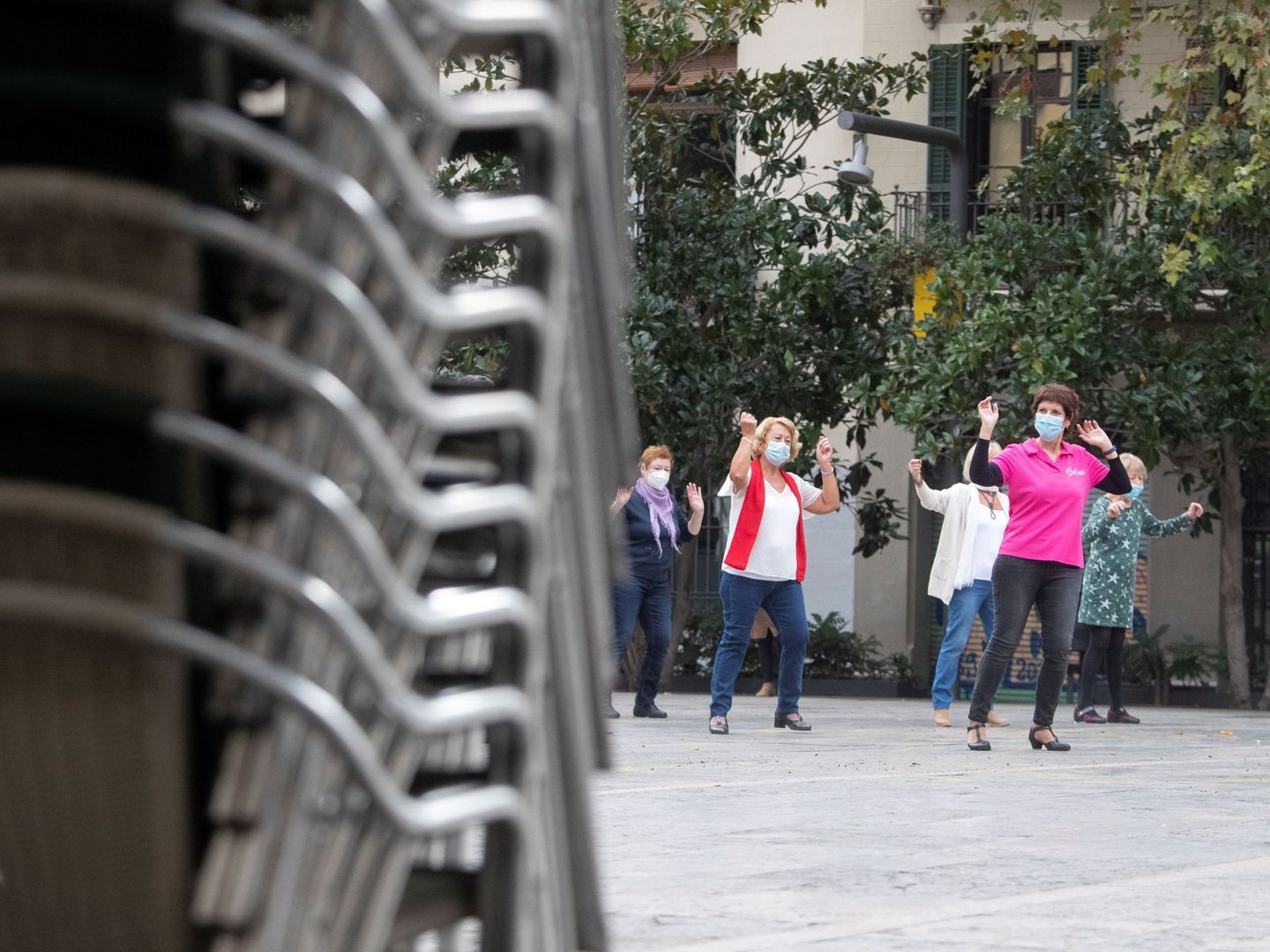 Varias mujeres hacen ejercicio en una plaza del centro de Barcelona con las terrazas clausuradas. (EFE)