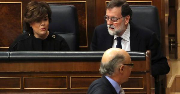 Foto: El exministro de Hacienda Cristóbal Montoro (abajo) pasa ante el expresidente del Gobierno Mariano Rajoy y la exvicepresidenta Soraya Sáenz de Santamaría en una sesión de control al Gobierno. (EFE)