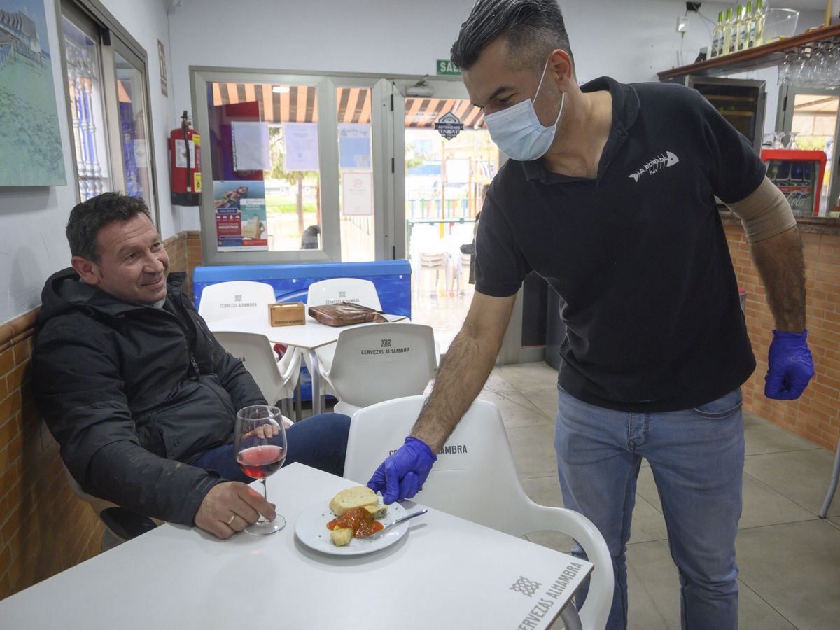 Foto: Un camarero sirve una tapa a un cliente en un bar de Granada. (EFE/Miguel Ángel Molina)