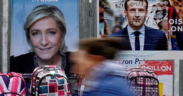 Foto: Una mujer pasa antes carteles de Le Pen y Macron en un mercado de Bethune, Francia. (Reuters)