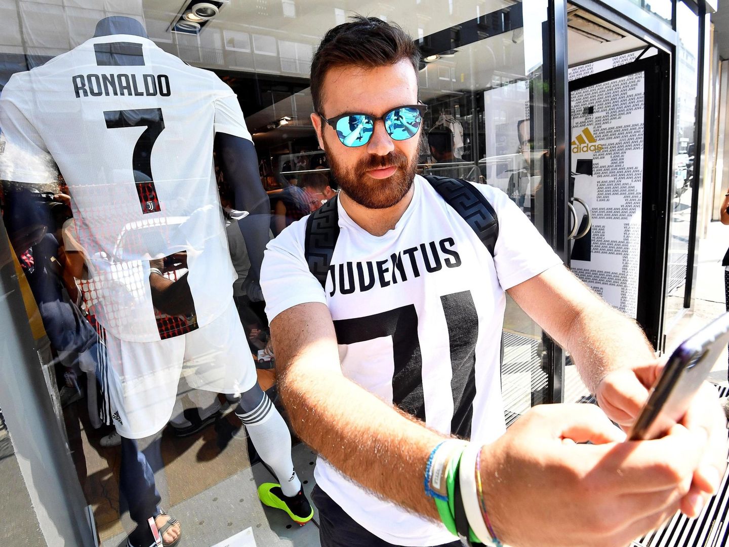 Un aficionado del Juventus posa con la nueva camiseta 'bianconera' que lucirá Cristiano Ronaldo frente a la tienda oficial del club en Milán, el 11 de julio de 2018. (EFE)