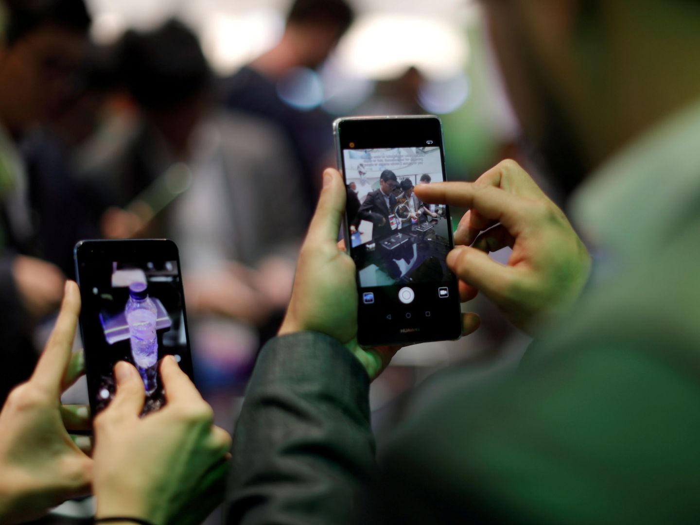 Dos visitantes del pasado Mobile World Congress prueban dos móviles en un stand. (Reuters)