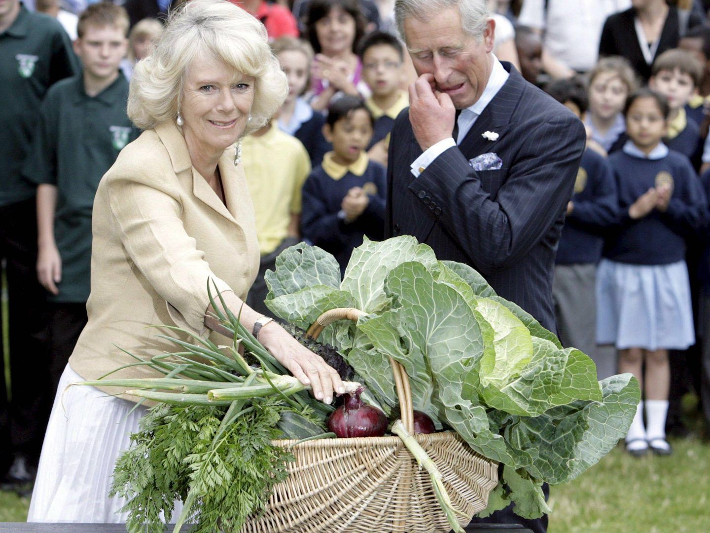 Camilla Parker y el príncipe Carlos de Inglaterra, tras recibir una cesta llena de verduras durante un encuentro con jardineros voluntarios en el parque de St. James. (EFE)