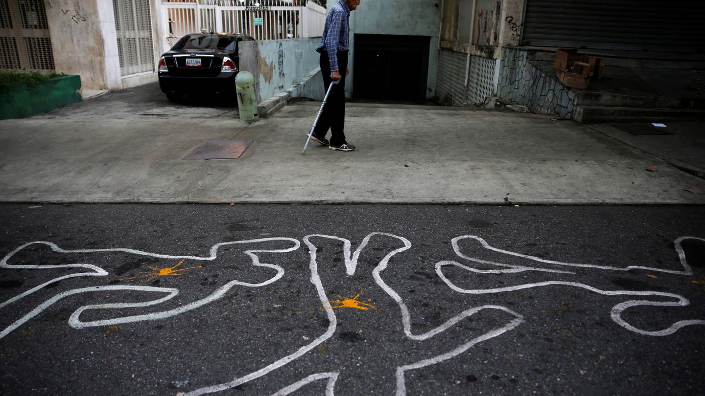 Un hombre camina ante contornos de tiza que representan a víctimas de la violencia, en Caracas. (Reuters)