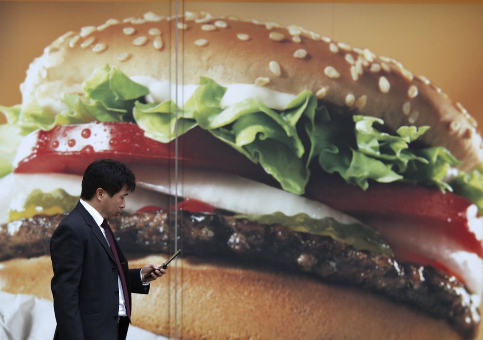 Foto: Un ejecutivo pasa frente a un anuncio de una hamburguesería en Tokio. (Reuters)