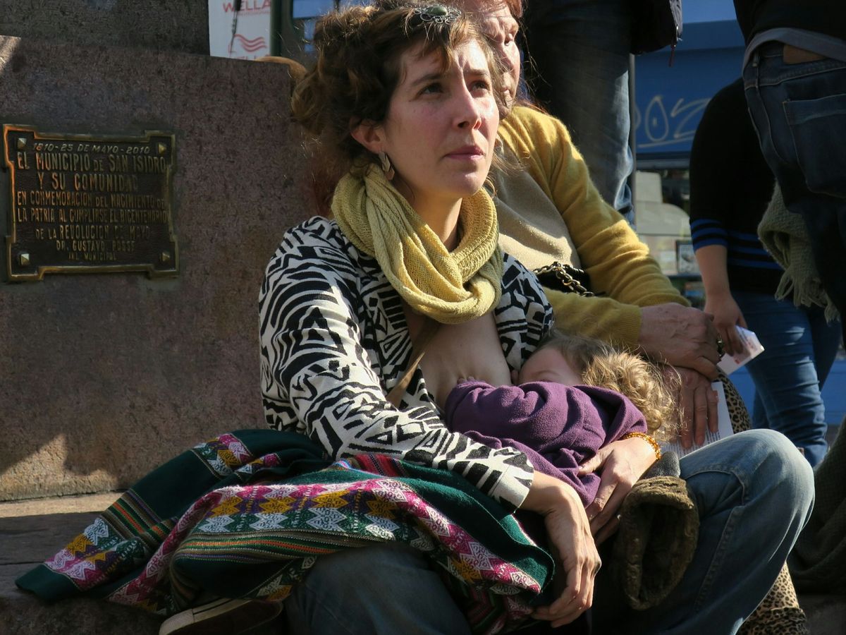 Foto: Una mujer da el pecho a su hijo en la calle. Foto: EFE IRENE VALIENTE