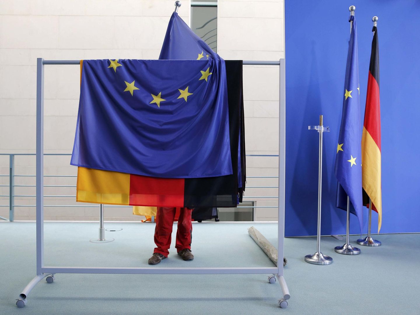 Una empleada prepara banderas de la UE y alemanas antes de una rueda de prensa en Berlín. (Reuters)
