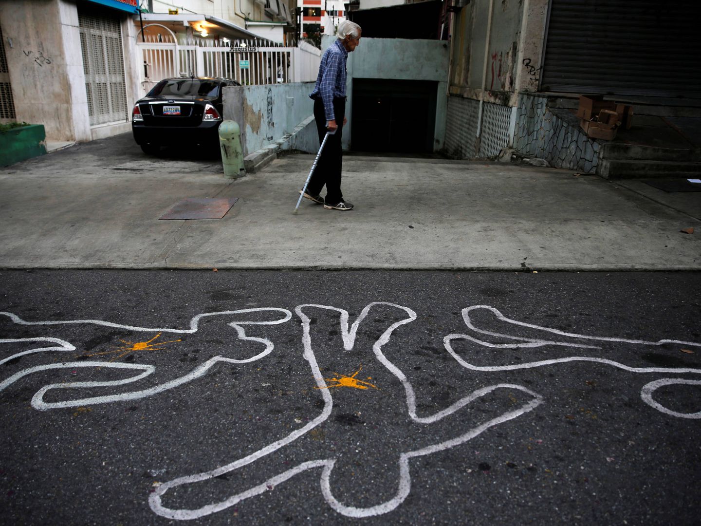 Un hombre camina ante contornos de tiza que representan a víctimas de la violencia, en Caracas. (Reuters)