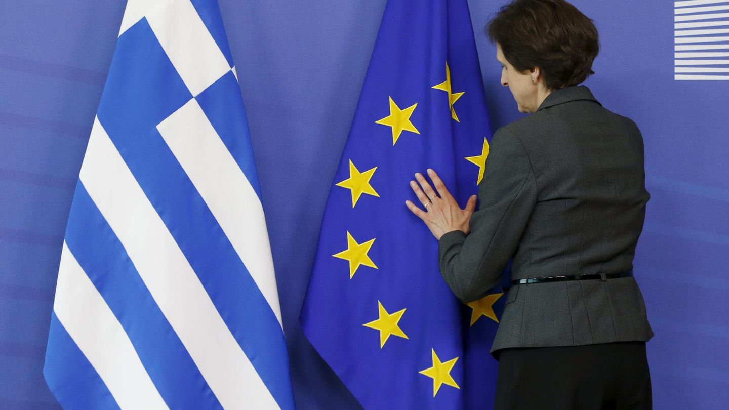 Una trabajadora arregla las banderas de Grecia y la UE. (EFE)