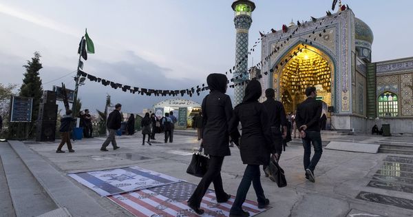 Foto: Iraníes pasan sobre una bandera de EEUU y otra de Israel en la entrada de una mezquita en el norte de Teherán. (Reuters) 
