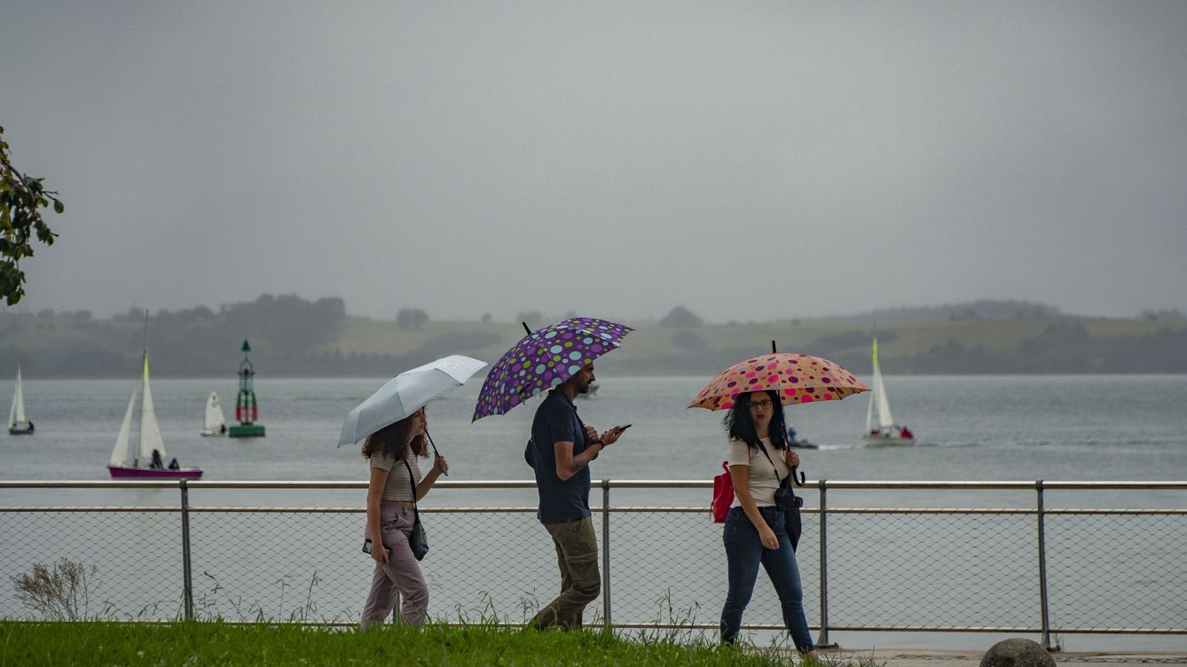 Foto: Varias personas se protegen con los paraguas de la lluvia. (EFE/Román G. Aguilera)