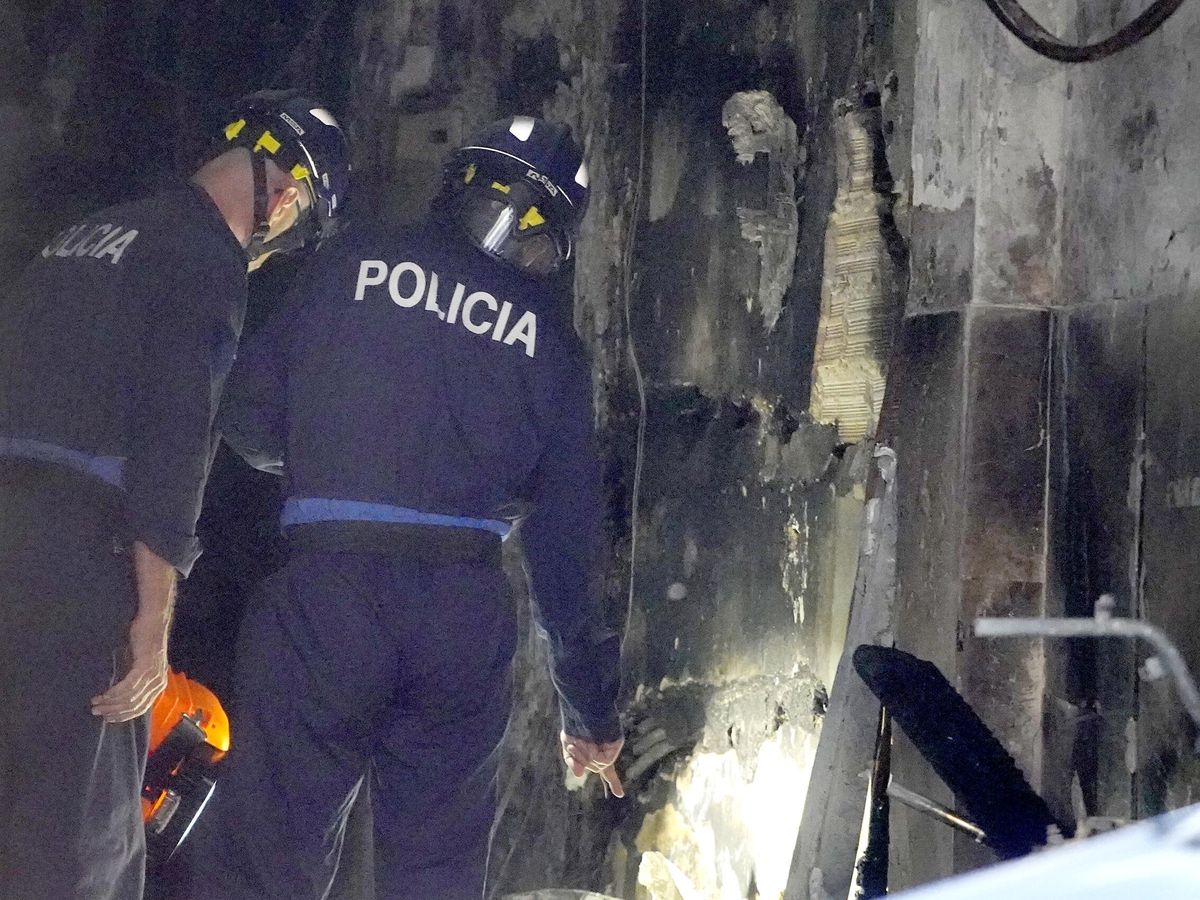 Foto: Dos agentes de la Policía trabajan en el edificio okupado de Vigo en el que murieron cuatro personas. (Europa Press/Javier Vázquez)