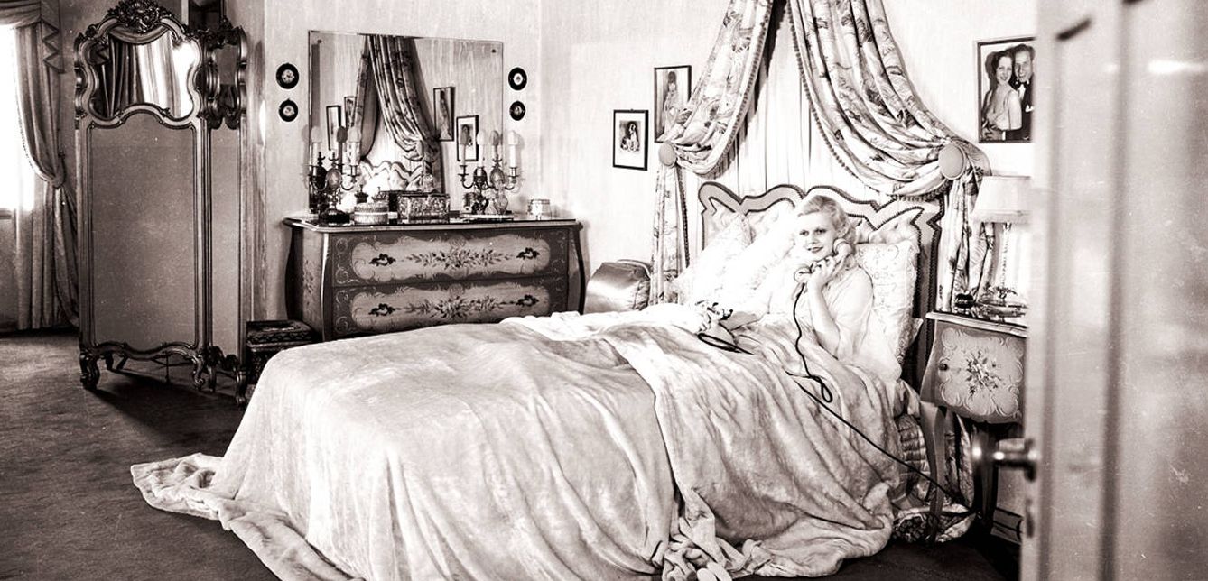 La estrella de Hollywood Jean Harlow (1911 - 1937) en su dormitorio, llamando por teléfono desde su cama, en 1932.