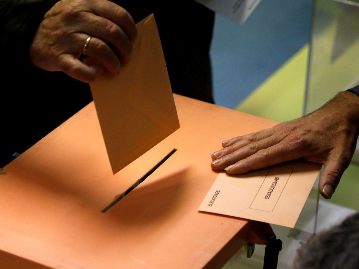Foto: Un elector deposita el sobre con las papeletas en una urna en el CEIP Ortega y Gasset de Madrid. (EFE)