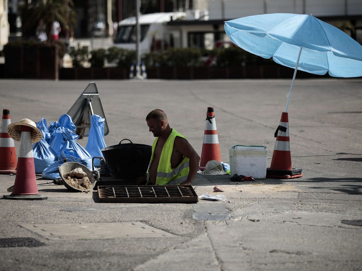 Foto: Un trabajador se protege del sol con una sombrilla en Valencia. (EFE/Ana Escobar)