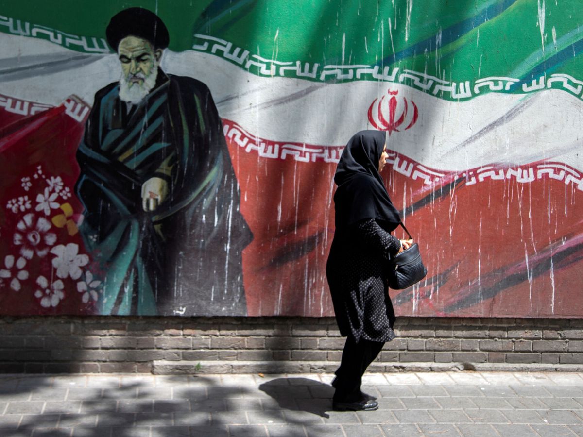 Foto: Mujer camina frente a un mural en Teherán. (Reuters)