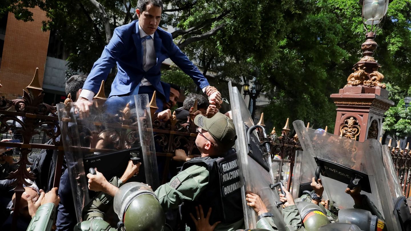 El líder opositor venezolano Juan Guaidó trepa una reja en un intento por ingresar a la sede de la Asamblea Nacional. (EFE)