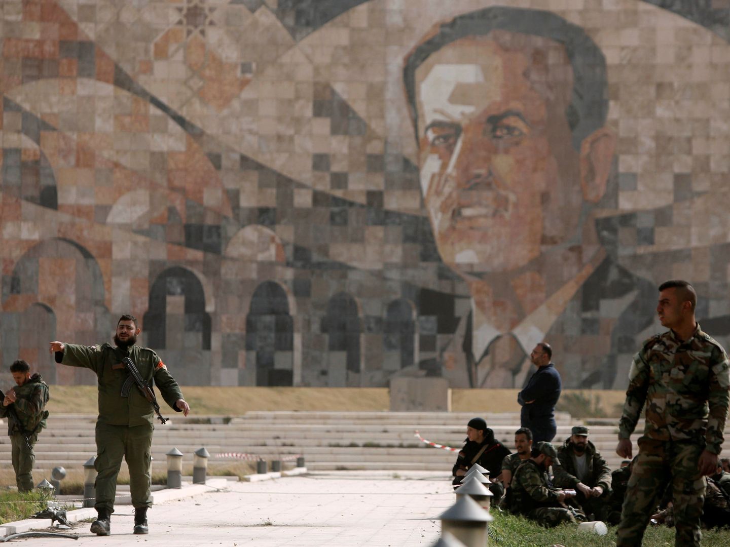 Soldados del ejército sirio frente a un mural de Hazef al Asad, padre del actual presidente, en Harasta, a finales de marzo. (Reuters)
