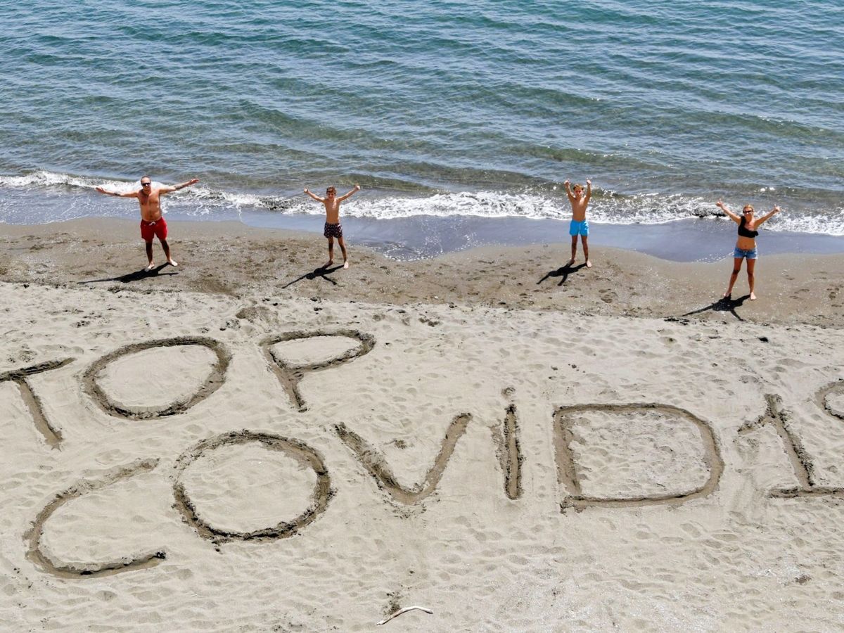 Foto: Una familia escribe la frase "Stop covid-19" en la arena de una playa de Nápoles, Italia. (EFE)