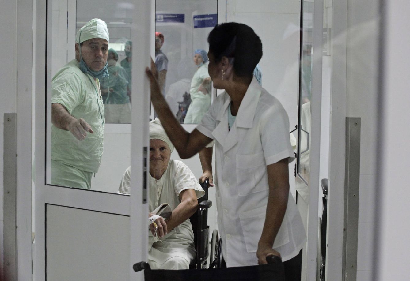 Personal de un hospital en Cienfuegos ayudan a una paciente en silla de ruedas tras una cirugía, en febrero de 2013. (Reuters)