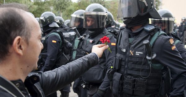 Foto: Un hombre ofrece un clavel a un agente de la Guardia Civil en el centro de votación de Sant Julià de Ramis (Girona). (EFE)