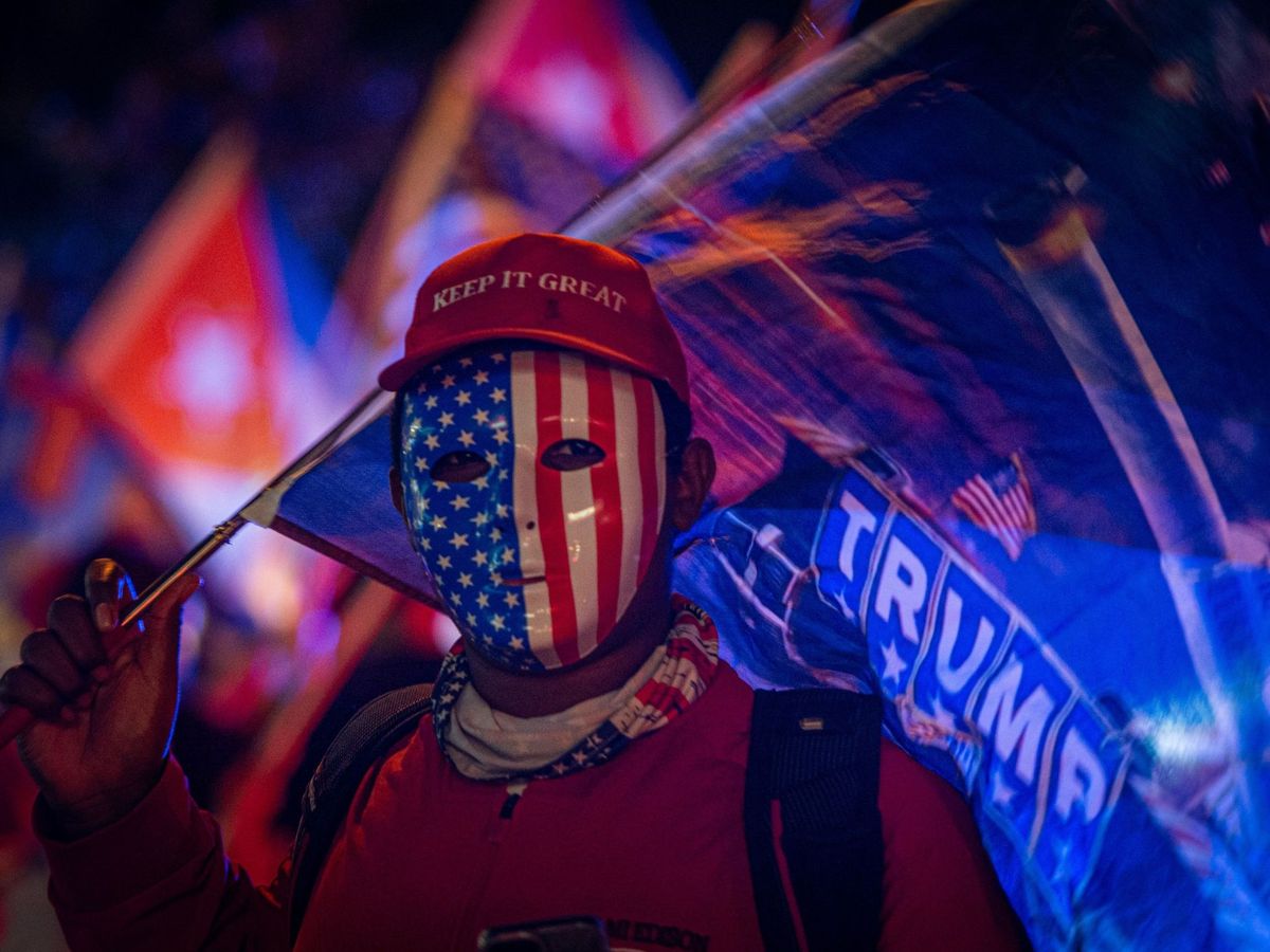 Foto: Un simpatizante de Donald Trump viste careta con la bandera estadounidense. (EFE)
