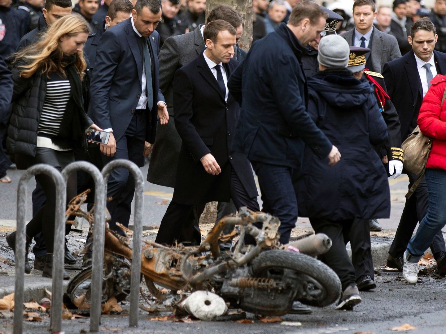 El presidente francés, Emmanuel macron, pasa junto a una motocicleta calcinada mientras comprueba personalmente los daños materiales ocasionados en las protestas, el 2 de diciembre de 2018. (EFE)