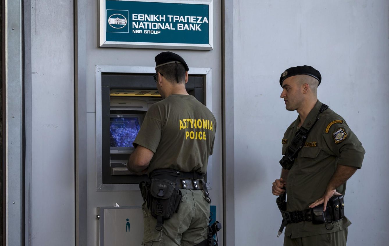 Varios agentes de policía sacan dinero en un cajero. (Reuters)