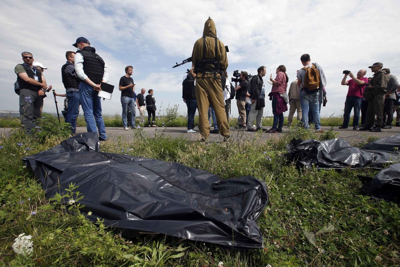 Investigadores de la OSCE y periodistas recorren el lugar del siniestro ante un combatiente prorruso. (Reuters)