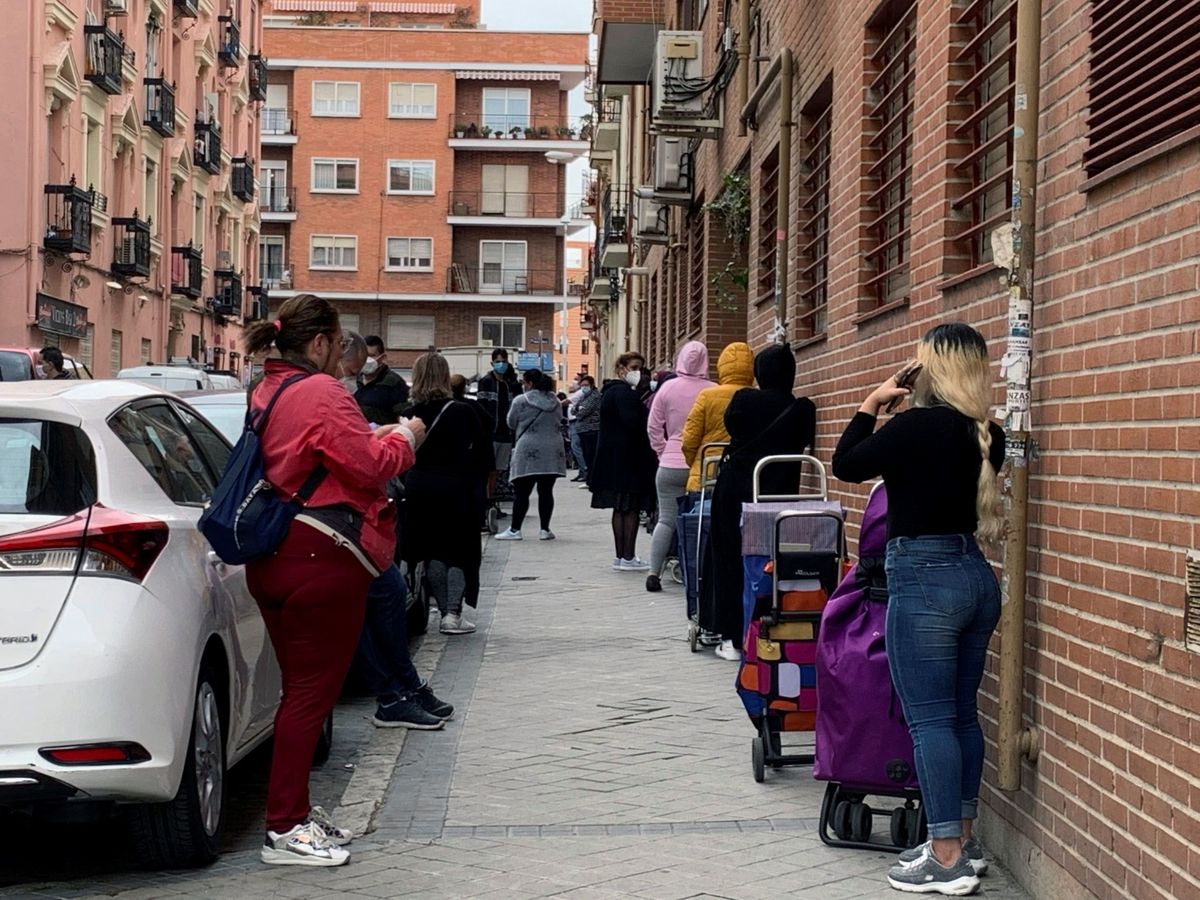 Foto: Fila de clientes que aguardan su turno para entrar al economato de Cárita. (EFE/Rafael Cañas)