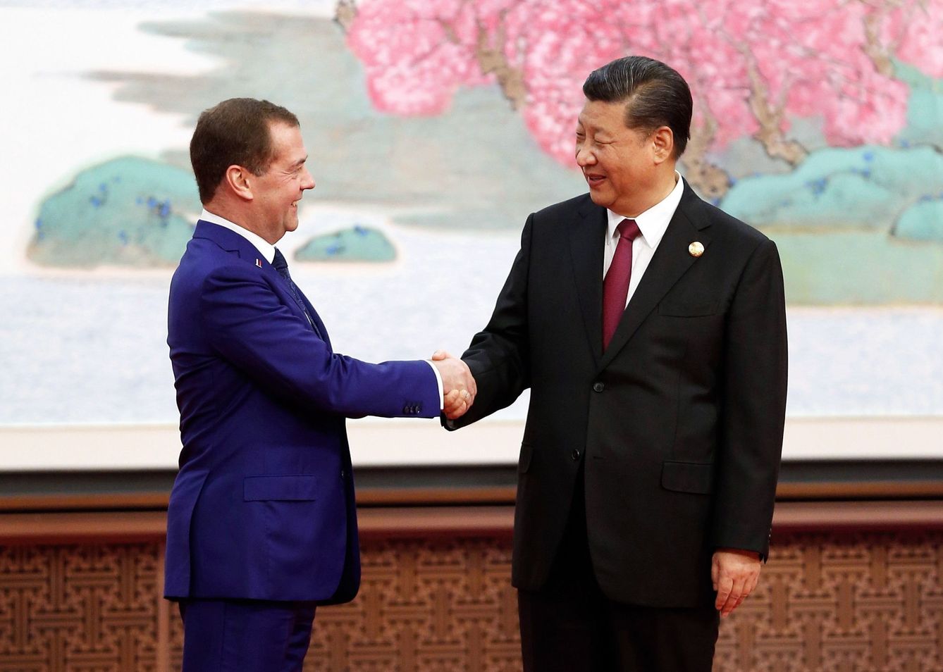 El primer ministro ruso, Dmitry Medvedev (i), estrecha la mano del presidente chino, Xi Jingping (d), durante una feria internacional de comercio. (EFE)