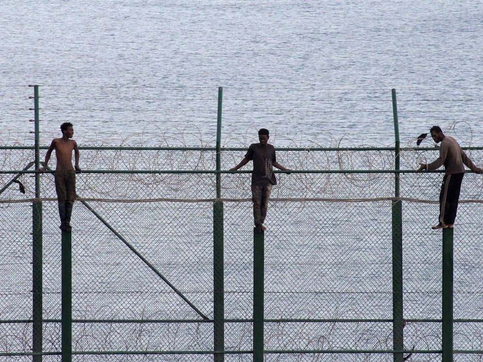 Foto: Más de un centenar de inmigrantes tras saltar la valla fronteriza con Ceuta (EFE).
