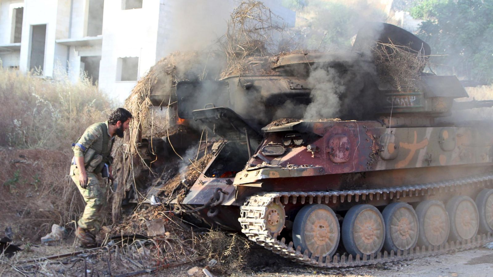 Foto: Un miembro del Frente Al Nusra inspecciona un vehículo antiaéreo en llamas tras la batalla de Ariha, en la provincia de Idlib (Reuters)