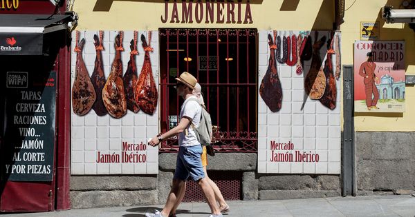 Foto: Turistas caminan frente a una tienda de jamones ibéricos. (Reuters)